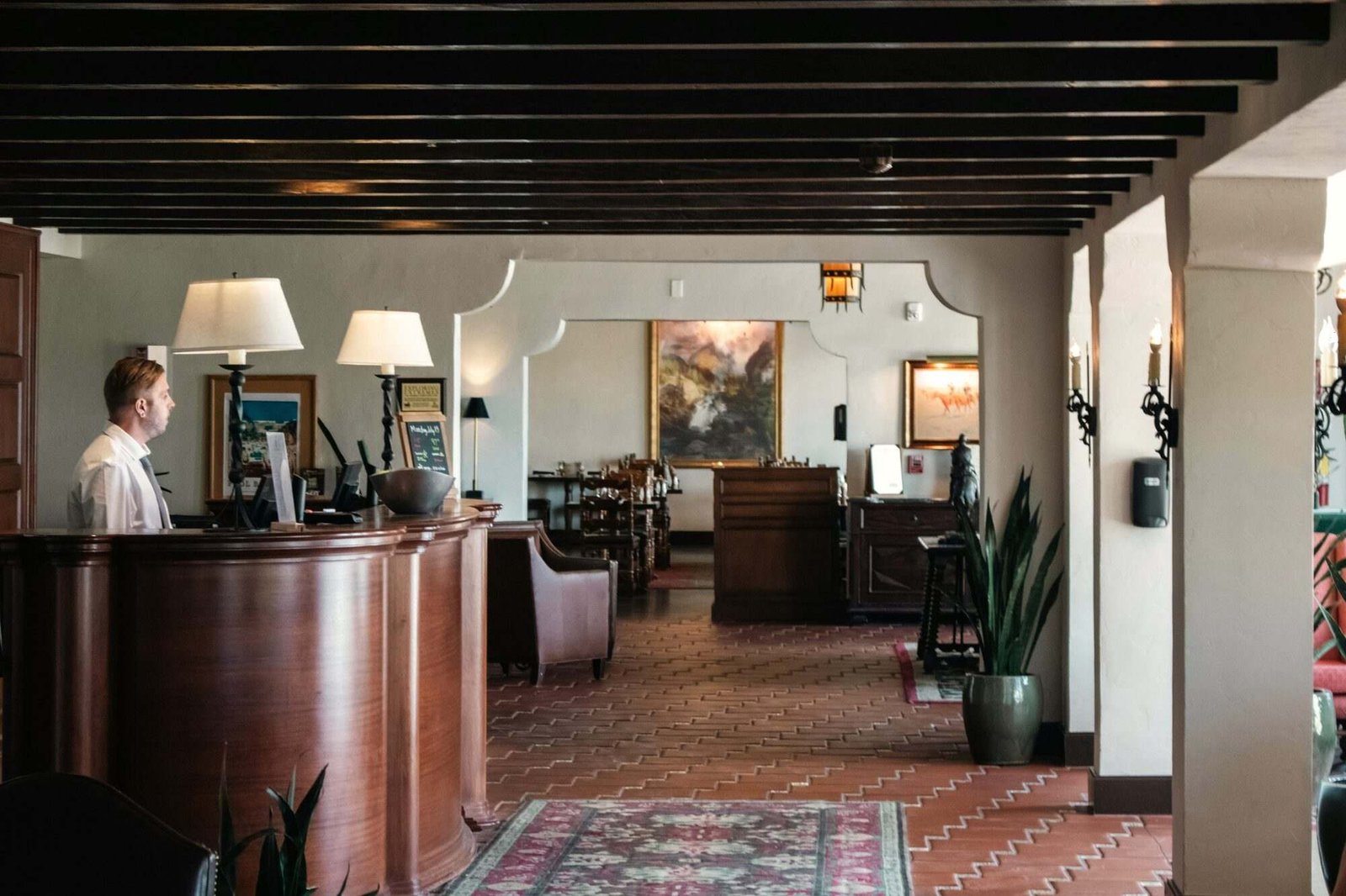 Rececionista no balcão de um pequeno hotel com sala de estar