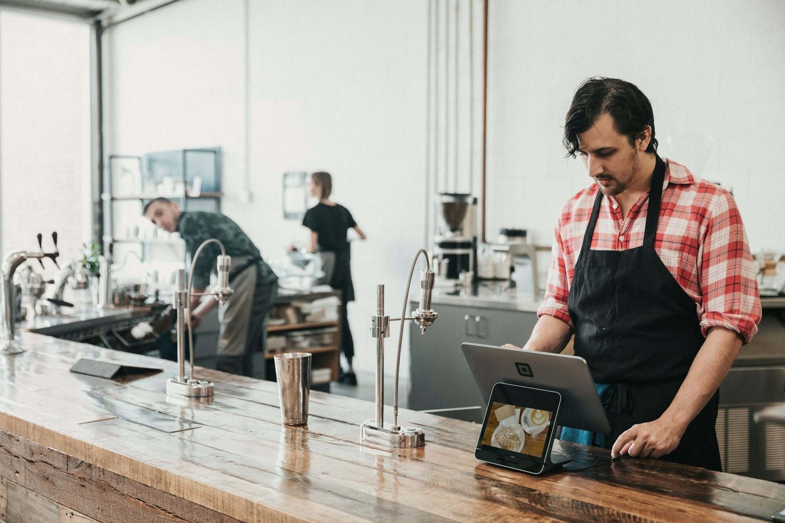 Responsável de um café a consultar reservas num tablet junto ao balcão