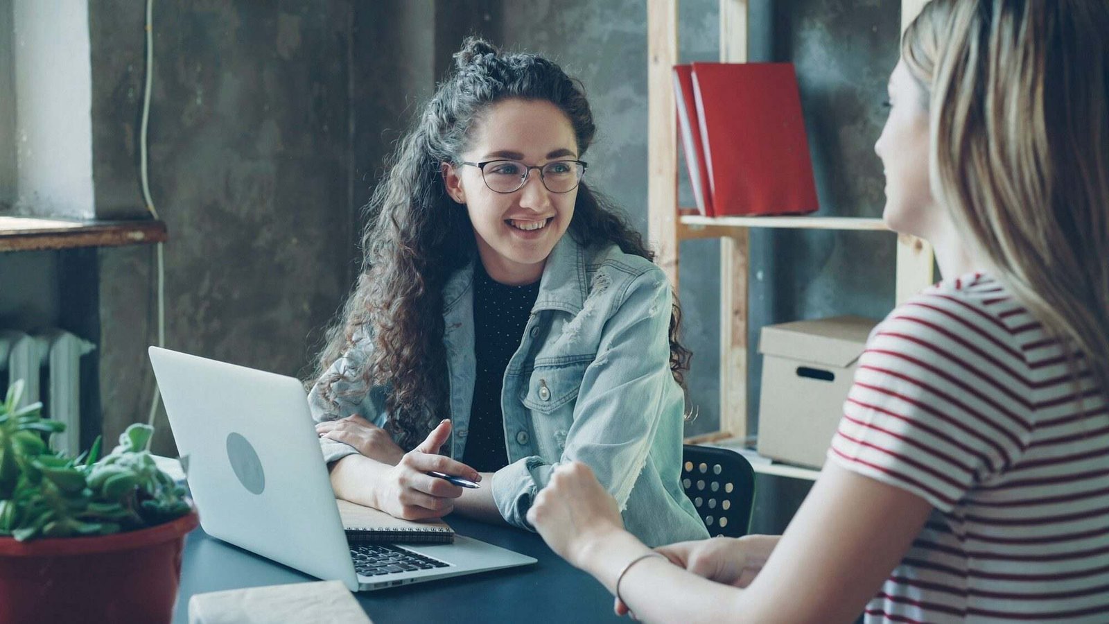 Dos personas conversando sobre un proyecto delante de un portátil
